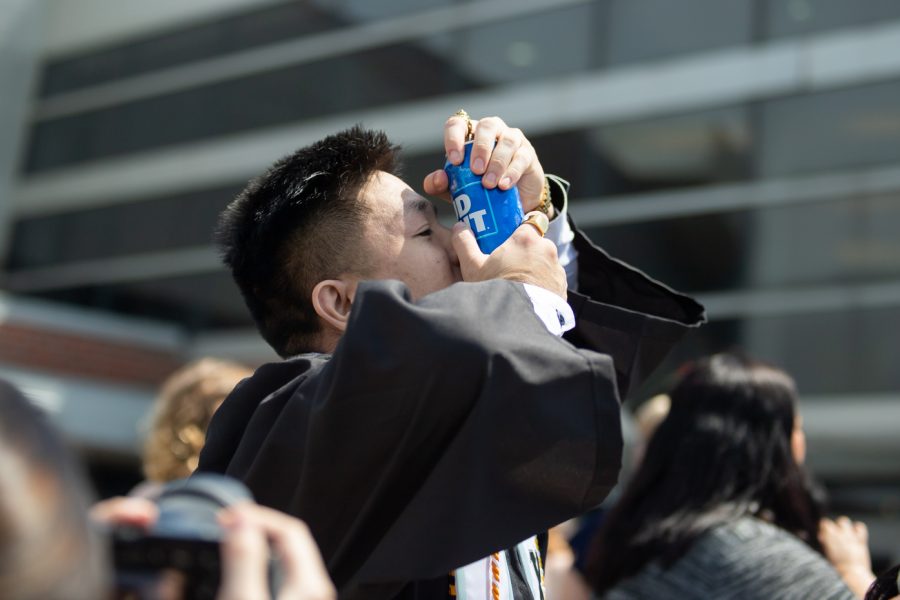 A graduate student chugs a can of Bud Light outside of Koch Arena after the first Spring 2022 Commencement Ceremony.