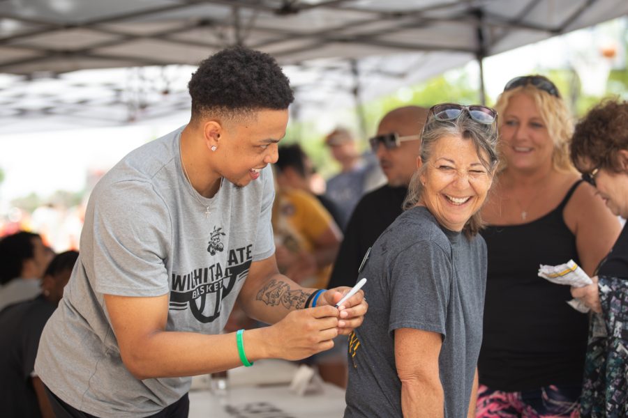 Freshman Xavier Bell signs a fans back at the 2022-2023 mens basketball team meet and greet during Riverfest.