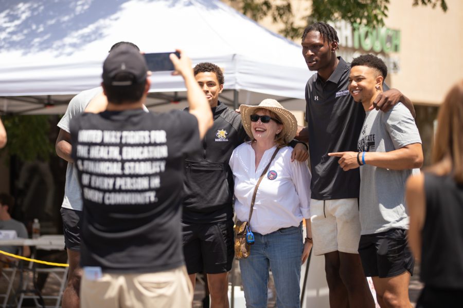The 2022-2023 mens basketball team poses with a fan during Riverfest on June 5.