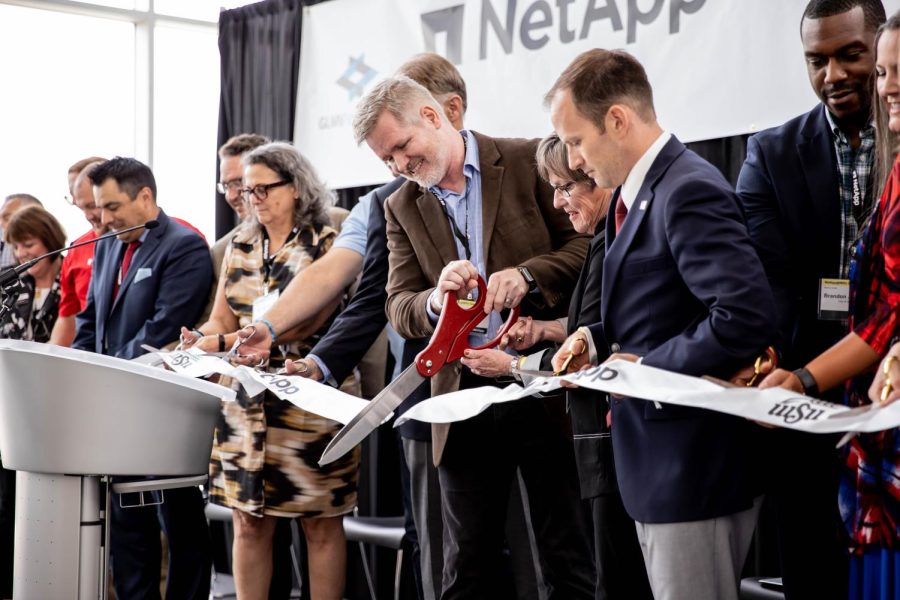 NetApp Vice President of Core Software & Data Management Robin Huber cuts the NetApp ribbon along with others involved with NetApp.