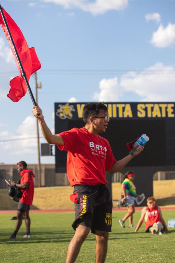 The College of Business waves their flag to cheer on their teammates during the dizzy bat portion of the Clash of Colleges. The College of Business won the Spirit Award on Aug. 26 in Cessna Stadium.
