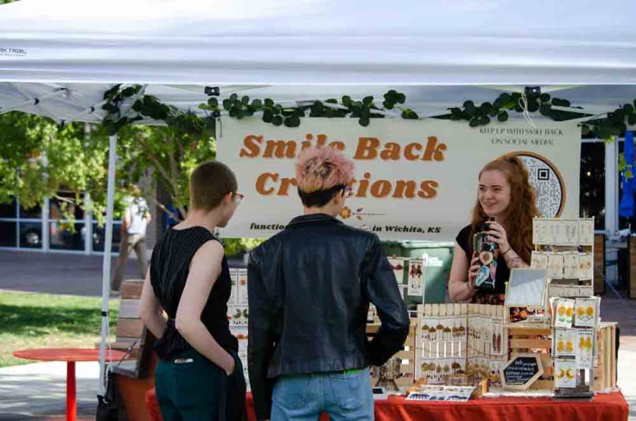 Passerbys stop and chat with Smile Back Creations. Smile Back Creation, run by Madison (right), specializes in handmade jewelery made with resin.
