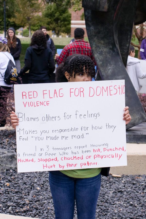 A Worldbuilders member holds a sign that details relationship red flags that are indicators of domestic violence. The Worldbuilders is a nonprofit that aims to make the world a better place one family at a time.