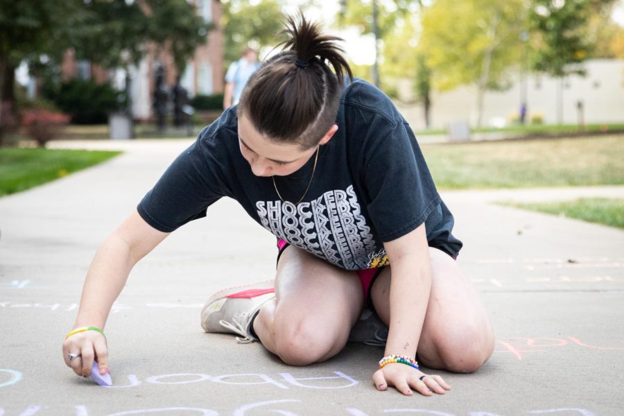 Aleecia Ketcher writes messages advocating for abortion rights, womens rights, and LGBTQ+ rights on the sidewalk of the RSC North patio on Oct. 6, 2022. Members of FOCUS (Feminists On Campus Uniting Students) and CatCallsOfICT mentioned that there were students who walked past and told them other topics to write about as well.