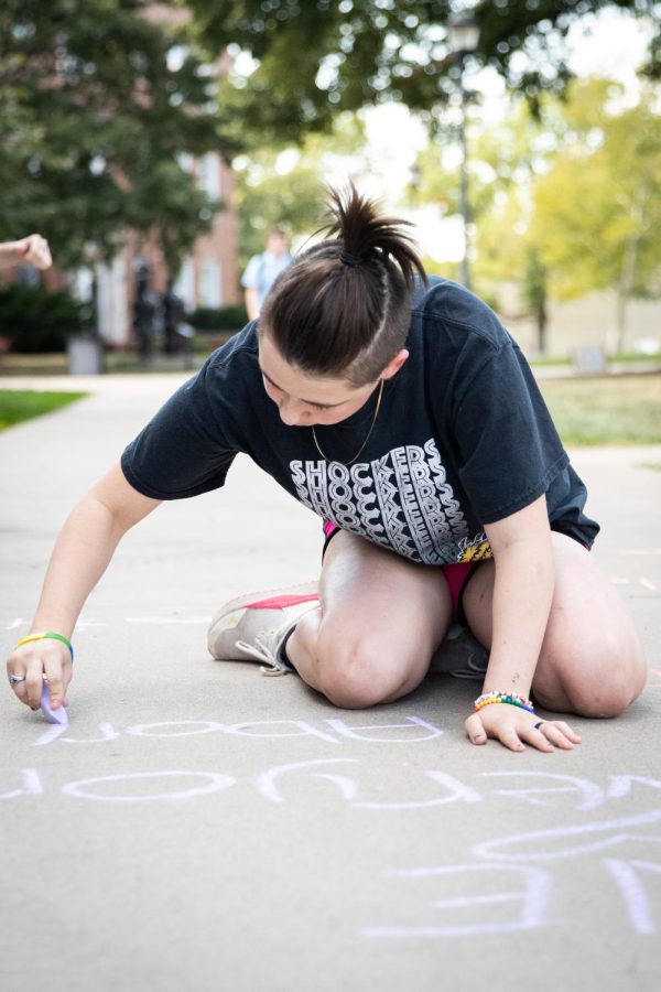 Aleecia Ketcher writes messages advocating for abortion rights, womens rights, and LGBTQ+ rights on the sidewalk of the RSC North patio on Oct. 6, 2022. Members of FOCUS (Feminists On Campus Uniting Students) and CatCallsOfICT mentioned that there were students who walked past and told them other topics to write about as well.