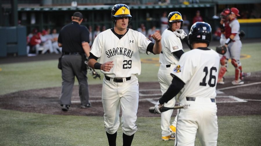 Outfielder Sam Hillard high fives a teammate after scoring a run. Hillard played one season for the Shockers before being drafted by the Colorado Rockies in the 15th round.  