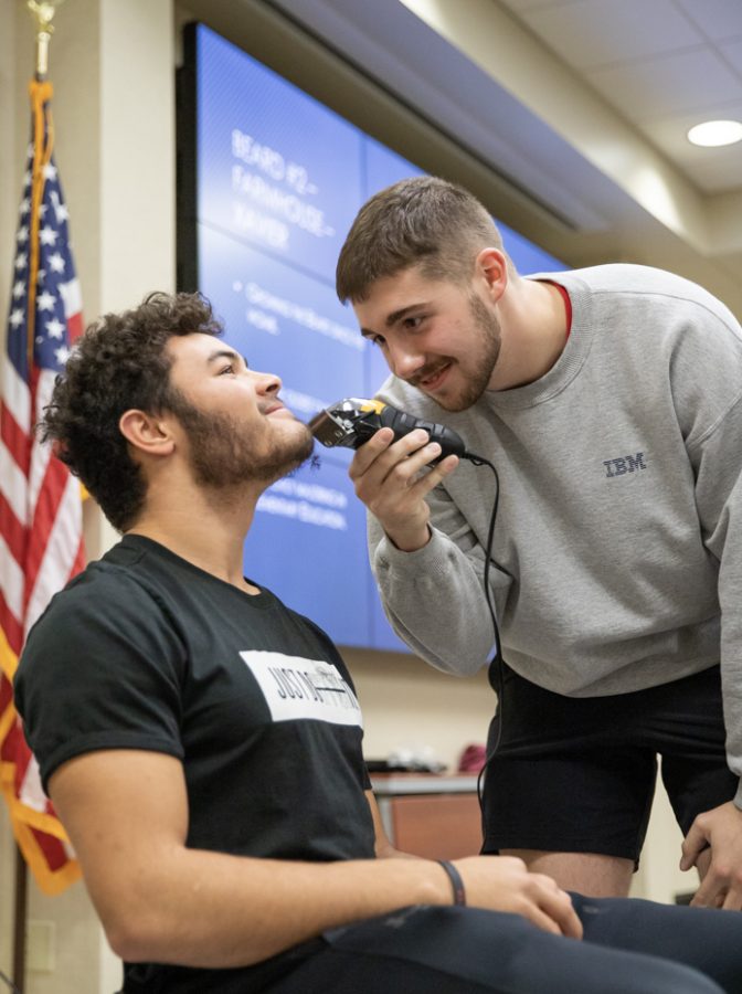 Xavier Westbrook, elementary education major, tilts his head up while Aden Lemasters, Sigma Phi Epsilon member, shaves his beard after offering the most during auction.