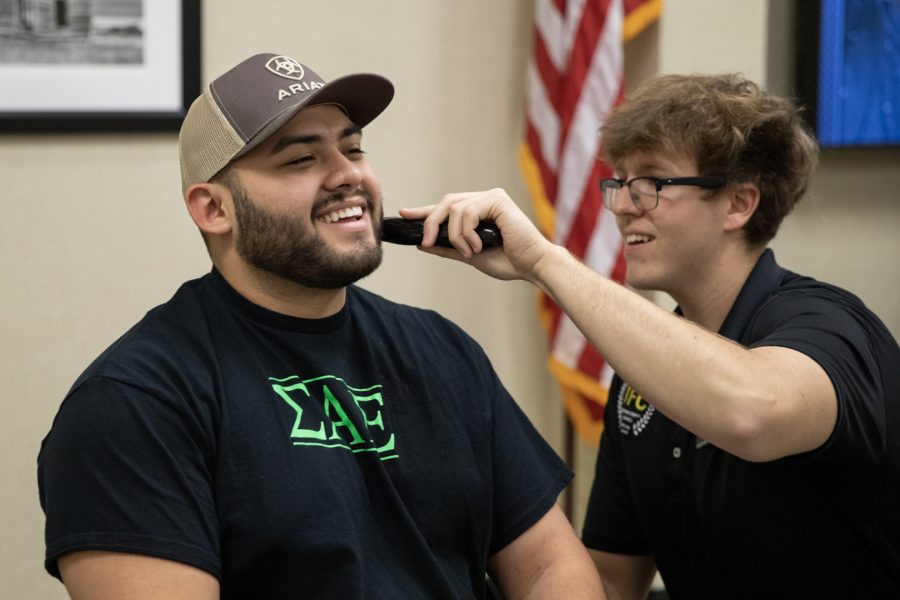 Carlos Martinez, Sigma Alpha Epsilon member, laughs while Colin Corwell, director of recruitment in the Interfraternity Council, shaves his beard.