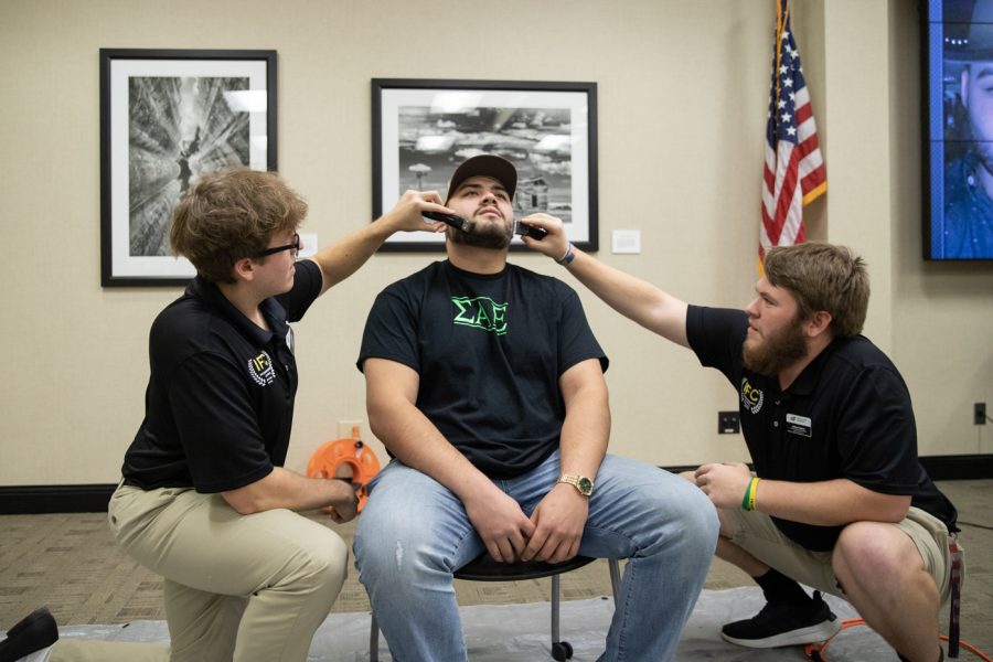 Colin Corwell, director of recruitment in the Interfraternity Council, shaves Carlos Martinezs beard alongside Jackson Ozanne, vice president of administration in the Interfraternity Council.