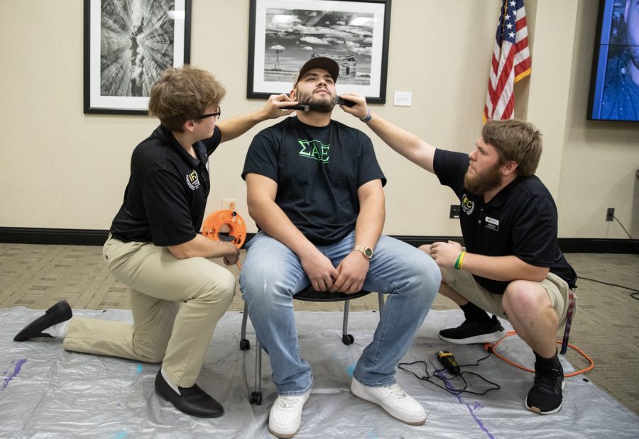 Colin Corwell, director of recruitment in the Interfraternity Council, shaves Carlos Martinezs beard alongside Jackson Ozanne, vice president of administration in the Interfraternity Council.