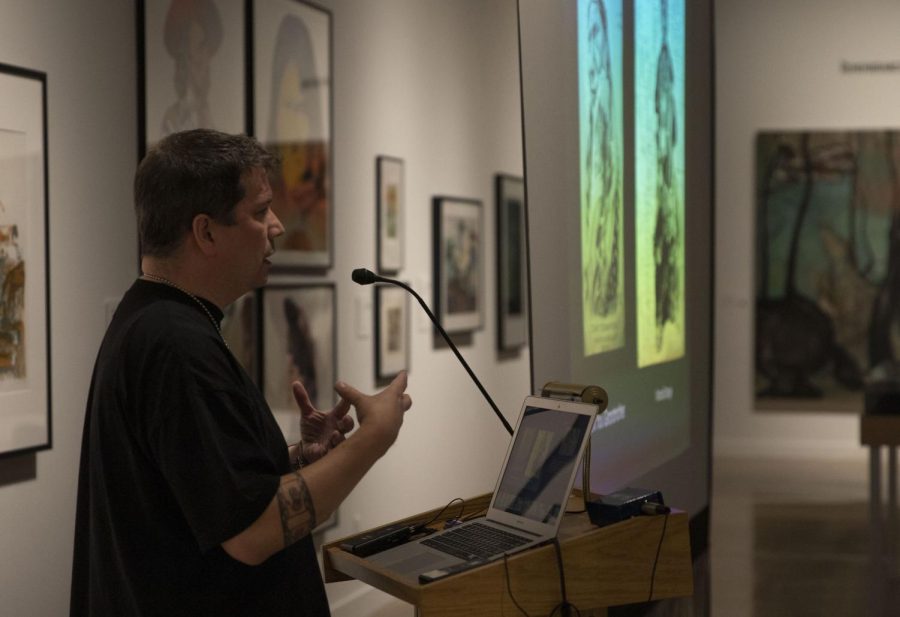 Chris Pappan discusses his different experiences as an artist in other cities Nov. 29 to his audience. He described having his work displayed in museums, how museums can improve their Native American exhibits and his future career steps. 