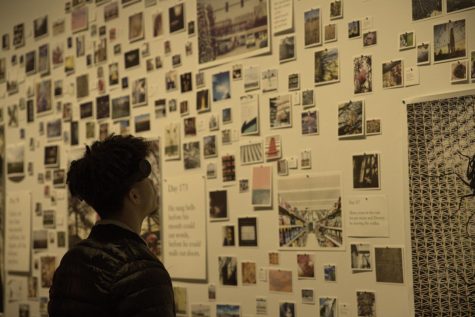 Student views the wall covered in pictures submitted by the artist to show days in their life
through abstract photos.
