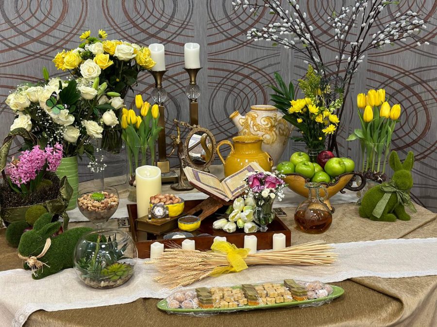 A Haft-seen table set up by Iranian Student Association members and friends and family of members. The table items consist of sprouted wheat/lentils, sweet pudding, dried oleaster fruit, garlic, apple, sumac and vinegar — all items represent different aspects of life and nature.