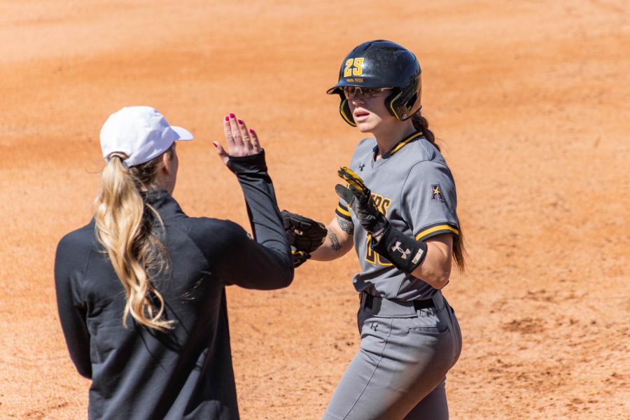 Sydney McKinney high fives assistant coach Presley Bell after reaching on fielders choice. 