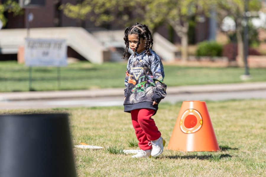 A young community member walks and plays with the various yard games available on April 29. Saturdays Cornhole Intramural Tournament offered raffles, food trucks, and yard games for everyone.