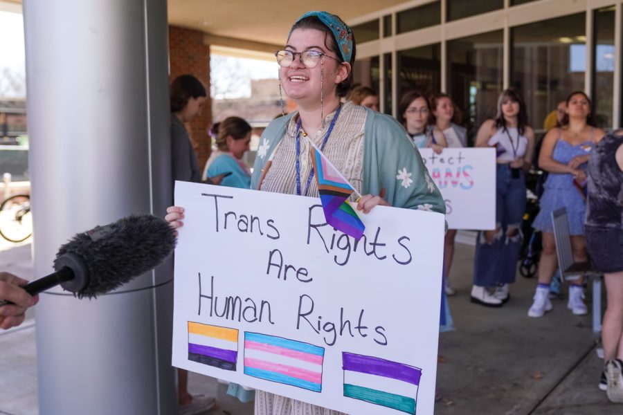 Mia Dennett, a film major, speaks to a reporter on Trans Day of Visibility on March 31. Students walked out of their classes, holding signs and pride flags .