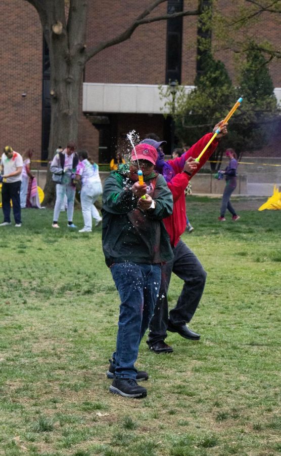 A Holi participant shoots a water pump during AHINSAs Holi celebration. Included in the entrance fee was access to colored powder, drinks, snacks and water guns.