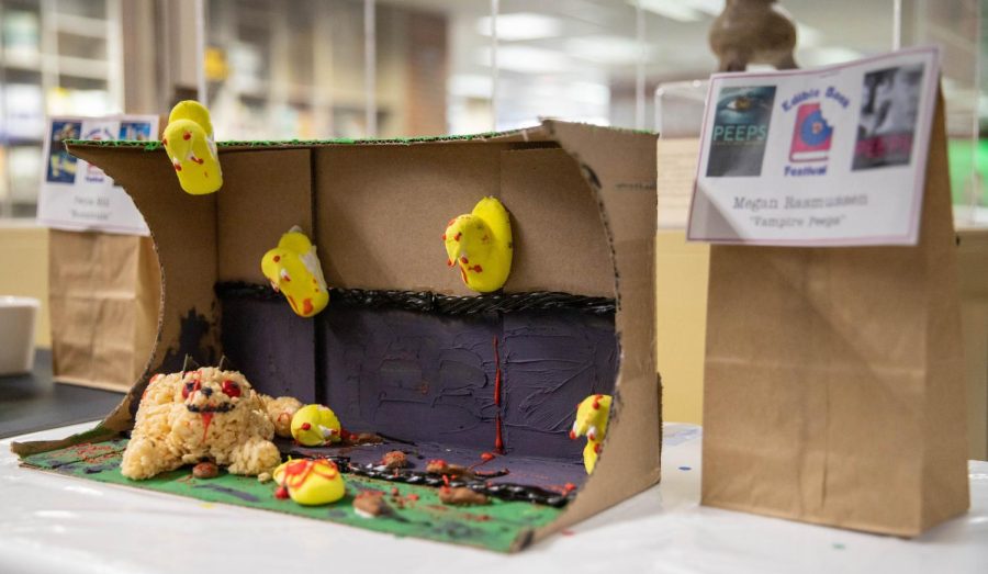 Peeps with fangs that are dotted with red frosting stuck to cardboard with a cat made of Rice Krispies at the bottom. It was created by Megan Rasmussen inspired by the book Peeps by Scott Westerfeld.
