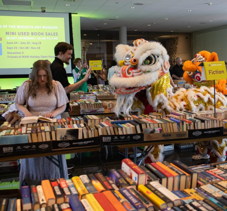 One of St. Anthonys Lion Dance performers checks out what a customer is reading during the WAM Book Sal.e. The St. Anthony team was one of many artistic groups invited to perform at the sale.