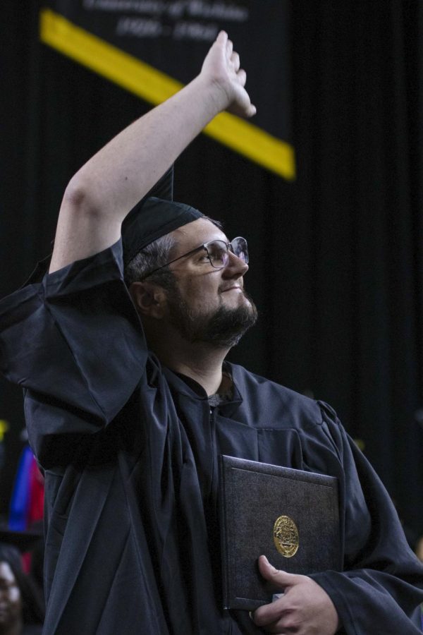 A graduate waves to friends and family during the spring graduation ceremony on May 13.