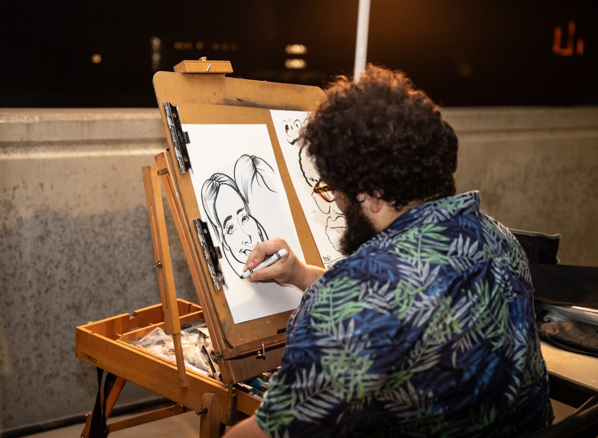 A caricature artist at the garage party draws attendees.
