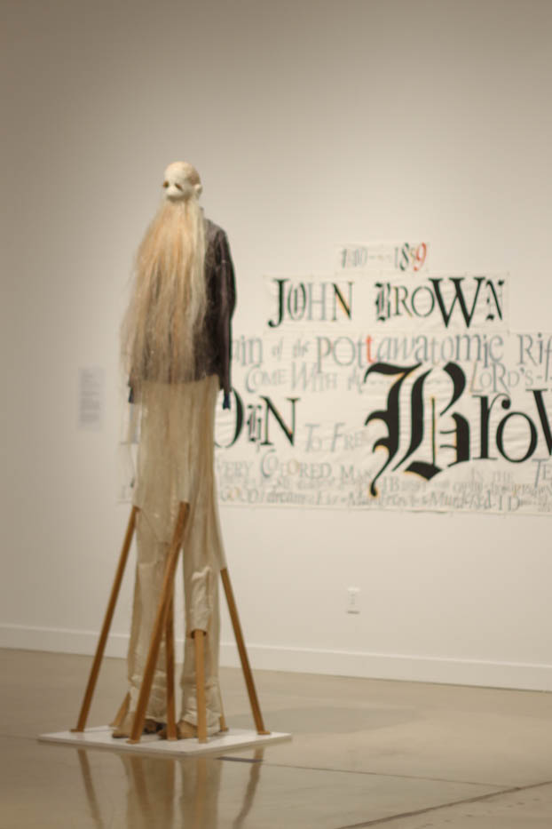 An effigy of John Brown next to a banner detailing the importance of the abolitionist.