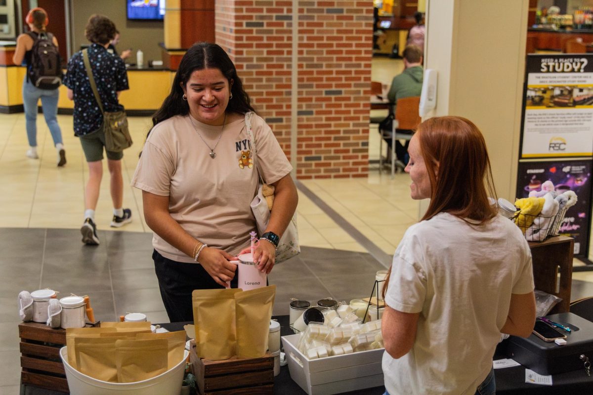 Sophomore Lorena Favella asks Shaina Wisbey about her business, Ablution Boutique, which offers a variety of self-care items like soap and candles.