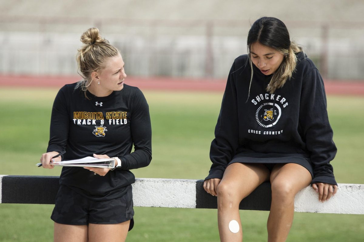 Aliyah Welters, an assistant coach for Wichita States track and field team, talks to a runner at Sept. 12s practice. Welters helps coach pole vaulters on the team.