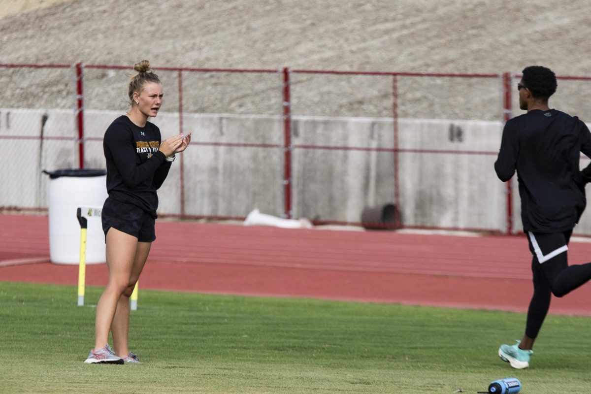 Aliyah Welters, an assistant coach for Wichita States track and field team, cheers on a runner at Sept. 12s practice. Welters helps coach pole vaulters on the team.