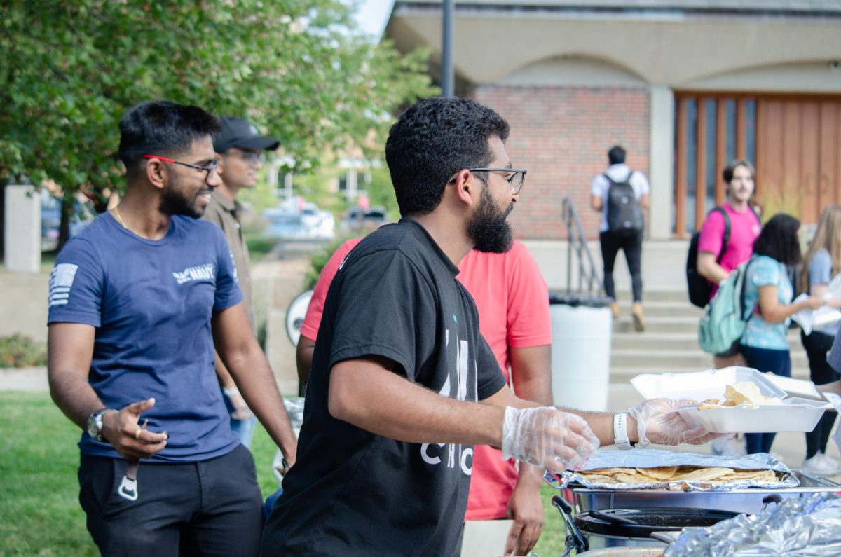 Randall DCruz serves homemade Indian food. On Sept. 27, students gathered to serve international cuisine for InterFest.