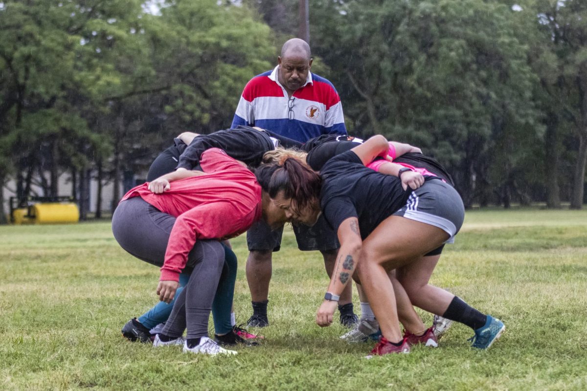 Wichita Valkyries rugby team members set up for a scrum. In rugby, forwards from each team push against each other in a scrum to obtain possession of the ball, which is thrown between the teams.