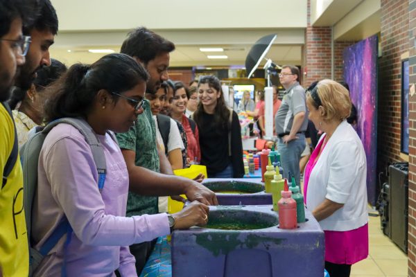 Two students pour colors onto a sheet of paper during a spin art piece activity featured at the RSCs Throwback Thursday event. The annual pop-up event features an assortment of freebies and snacks popular during the 80s and 90s.