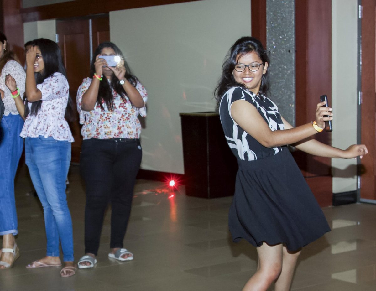 A student dances while a friend records and takes pictures at the Bollywood Night event on Sept. 2.