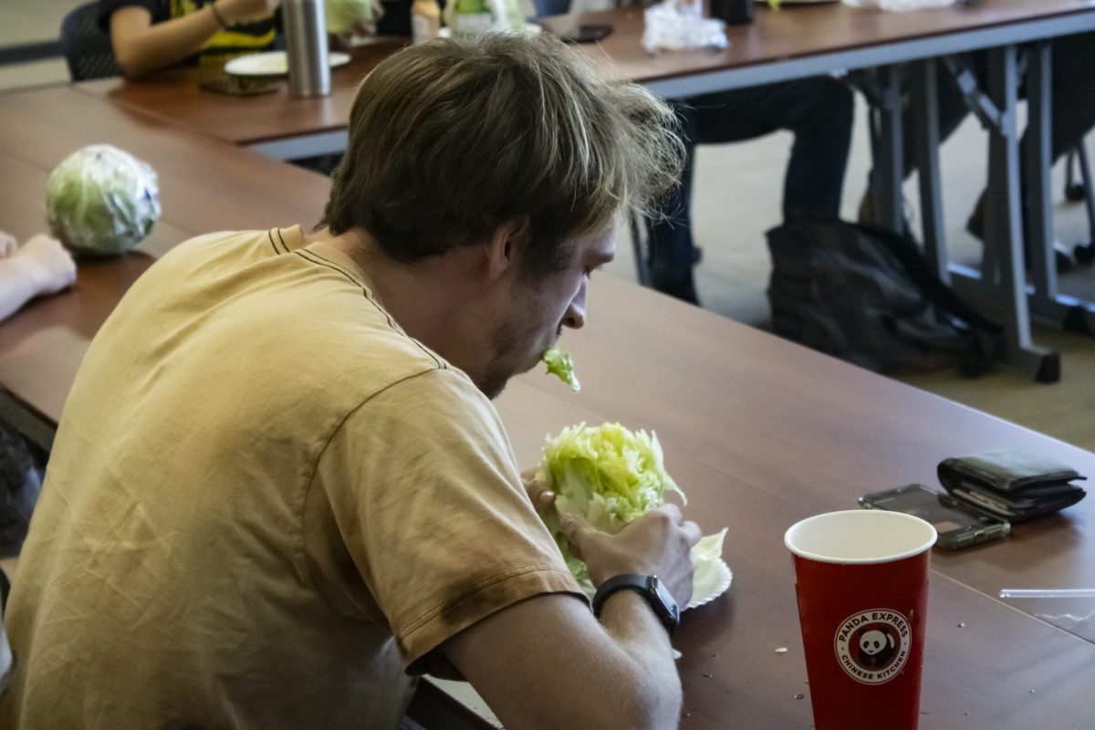 Wyatt Leutzinger, who was named Head Lettuce, begins eating his lettuce head at the second lettuce head eating competition held by Green Group on Oct. 11.