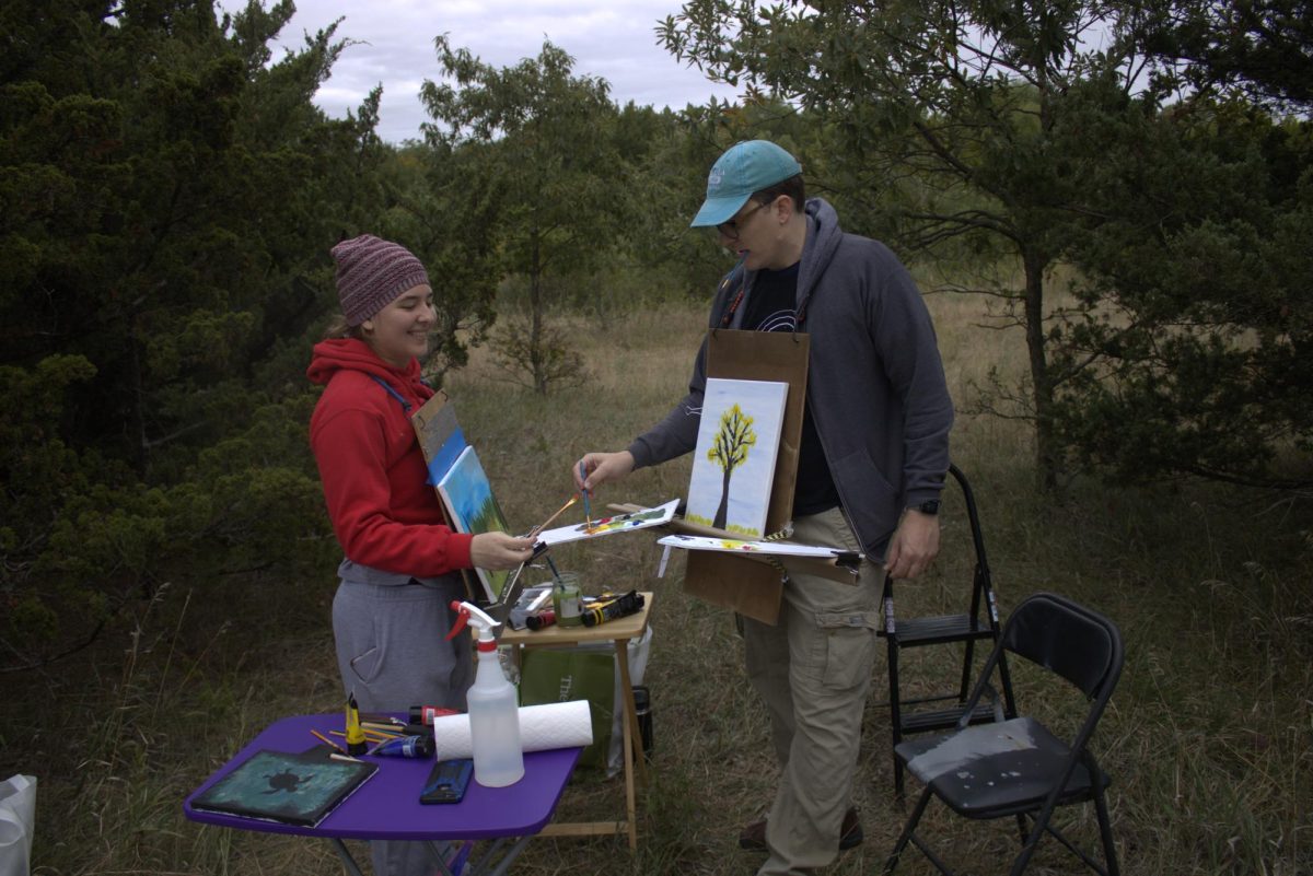 Daniel and Aubrey Mealiff paint on a canvas attached to their bodies on the hiking trail at the Great Plains Nature Center. Attendees had the chance to watch artists paint along the trail while chatting and drinking wine. 