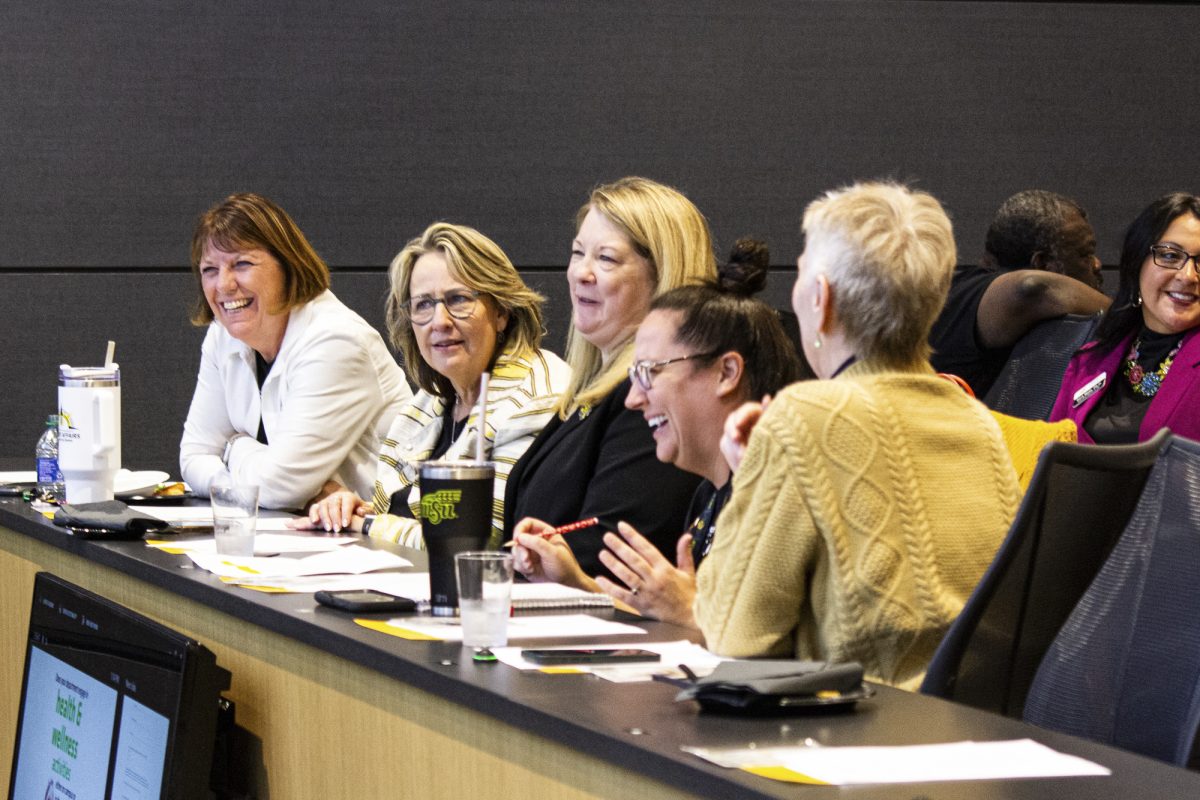 Shirley Lefever, Teri Hall, Vicki Whisenhant, and other employees at Wichita State laugh together. At the Wichita State Wellness event on Oct. 11, the audience was asked to talk to the people next to them about how to improve students mental health.