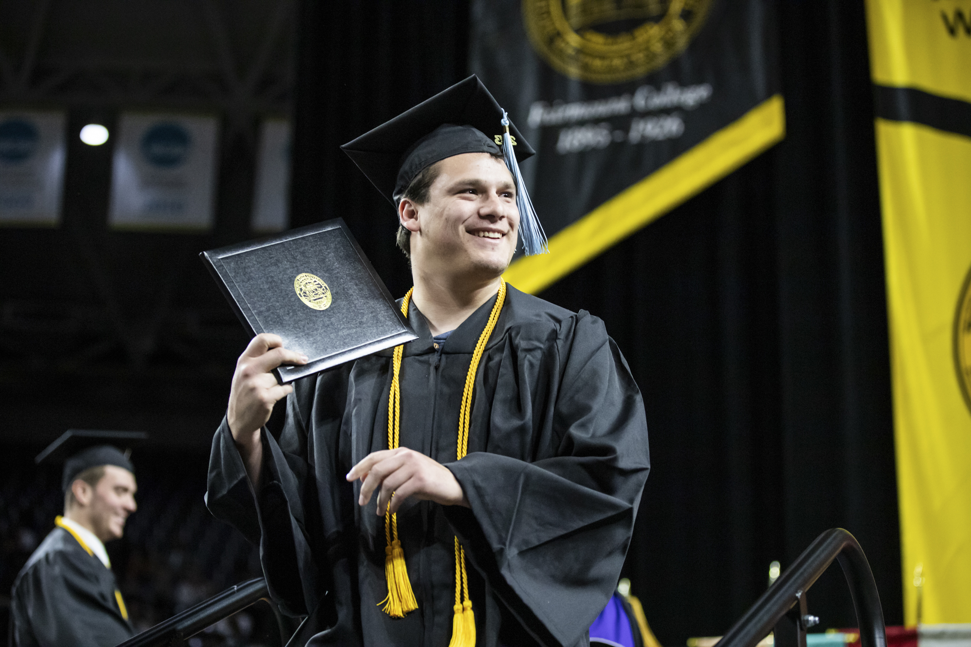 After walking the stage, a fall 2023 graduate holds up his diploma to family and friends in Charles Koch Arena on Dec. 17.