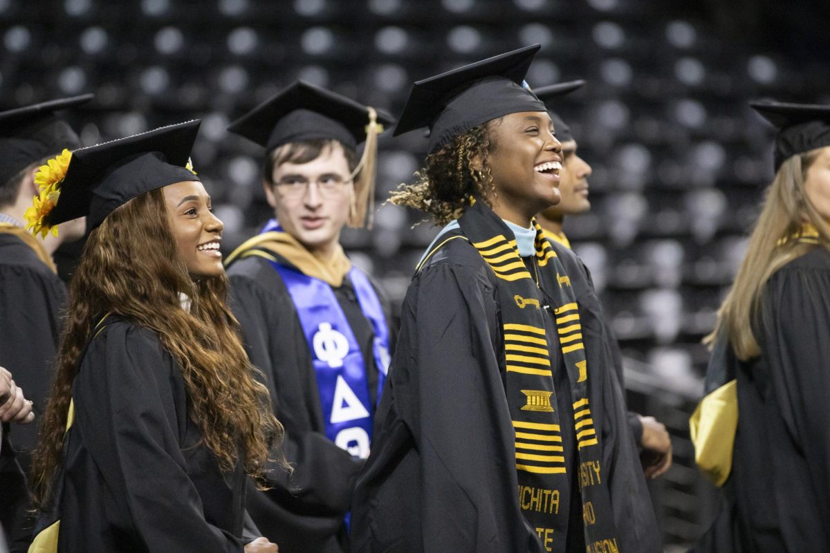 Fall 2023 graduates laugh while walking into Charles Koch Arena for the commencement ceremony on Dec. 17.