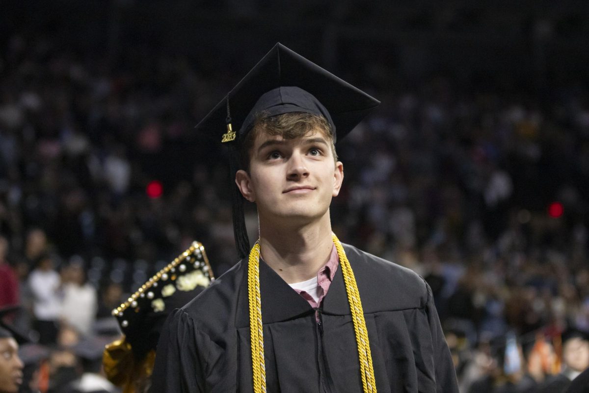 A fall 2023 graduate looks up into the crowd at Charles Koch Arena as graduates walk into the room for commencement on Dec. 17.