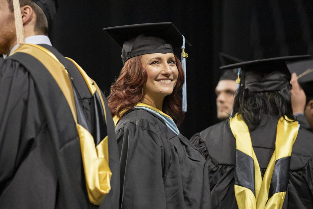 A fall 2023 graduate looks up into the crowd at Charles Koch Arena as graduates walk up to the stage to receive diplomas on Dec. 17.