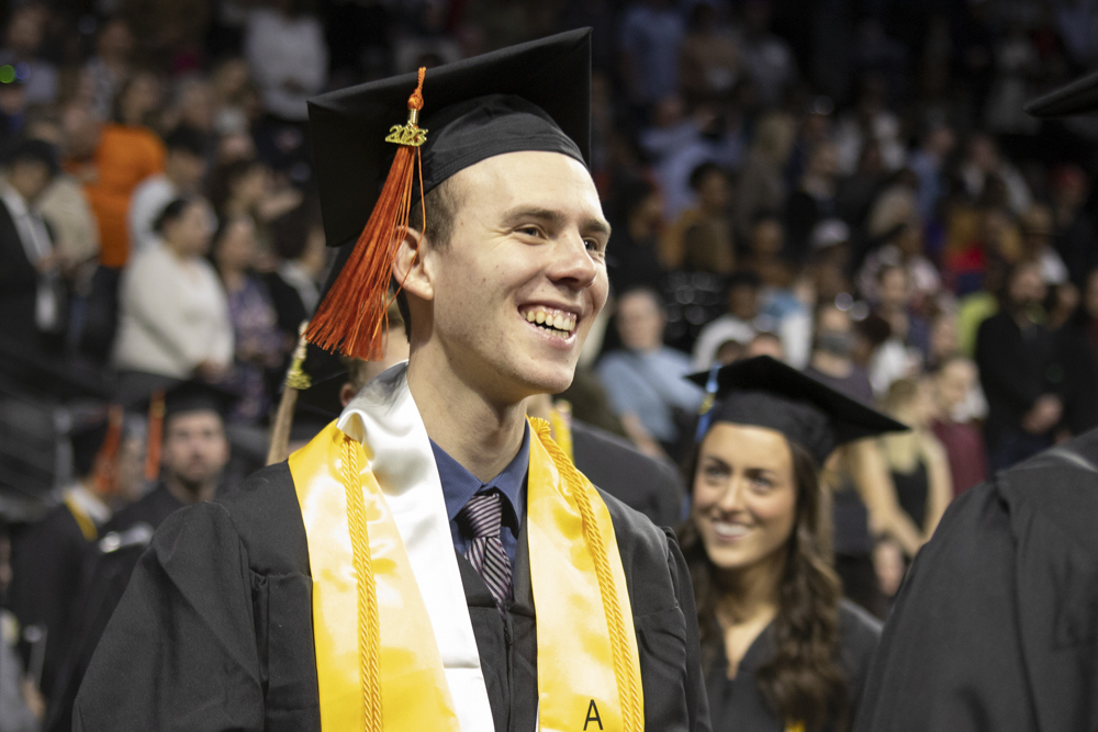 A fall 2023 graduate looks up into the crowd at Charles Koch Arena as graduates walk up to the stage to receive diplomas on Dec. 17.