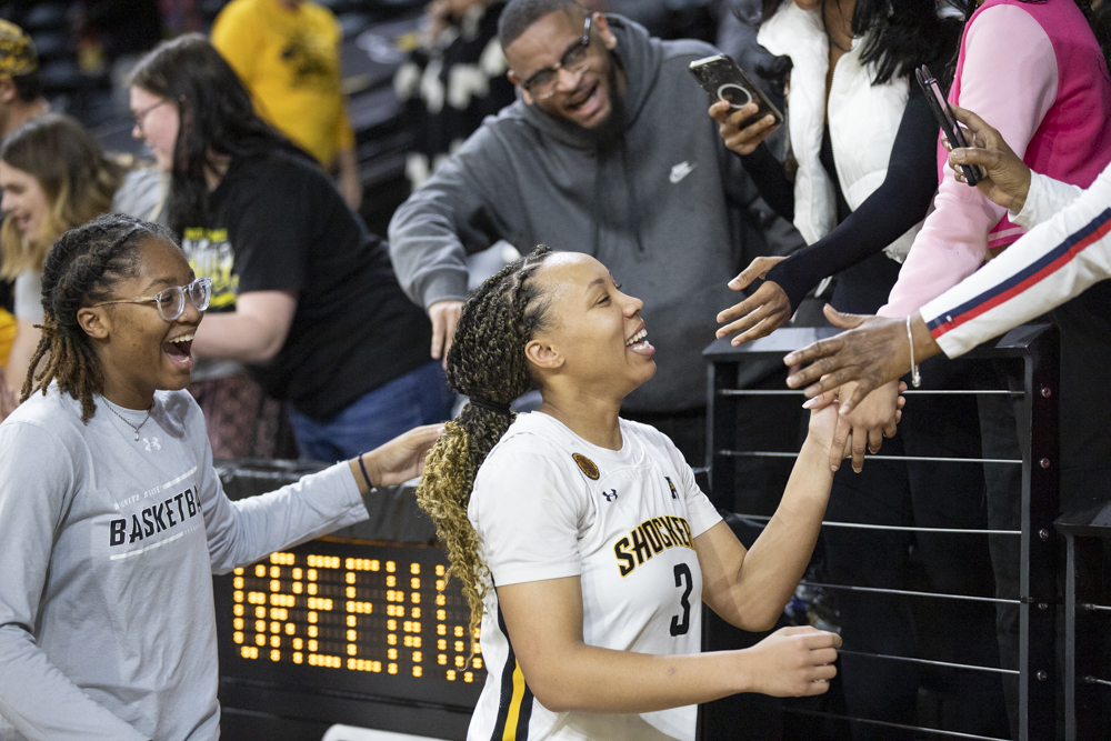 After defeating Tulane University, 63-60, DJ McCarty and TreZure Jobe high five and hold hands with audience members in Charles Koch Arena on Dec. 30.