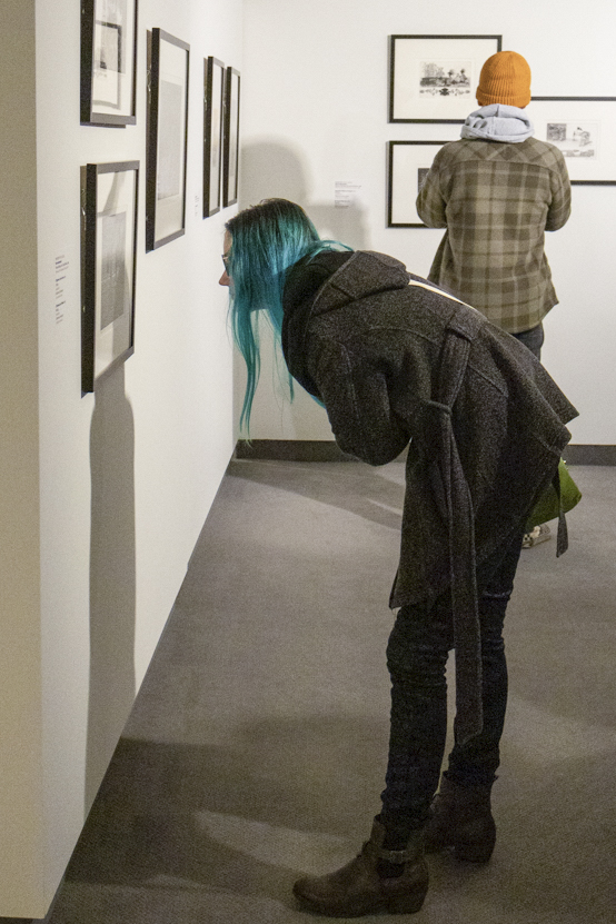 Artist Rachel Hermes looks closely at the prints displayed in Sin Perder A Mis Raíces (Without Losing My Roots), Marco Hernandezs gallery at the Wichita Art Museum. His gallery can be viewed at WAM until March 24.