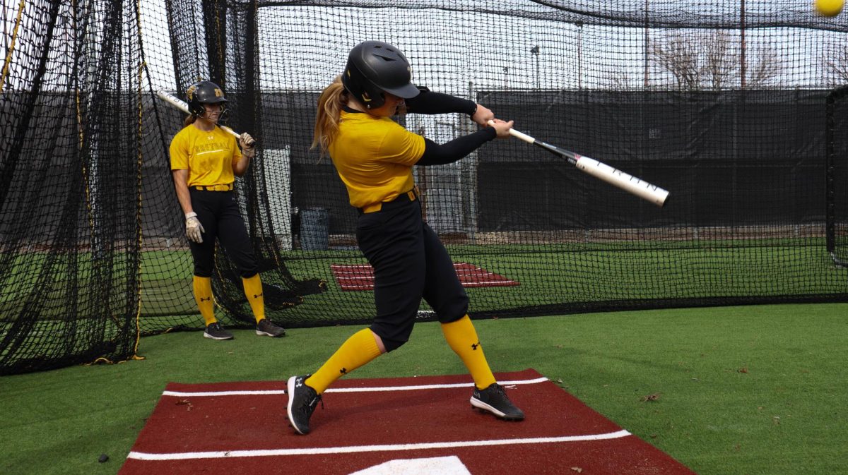 Senior outfielder Addison Barnard practices her hitting in the batting cage at Wilkins Stadium. Barnard and her younger sister, Avery Barnard, both play for the Wichita State softball team.
