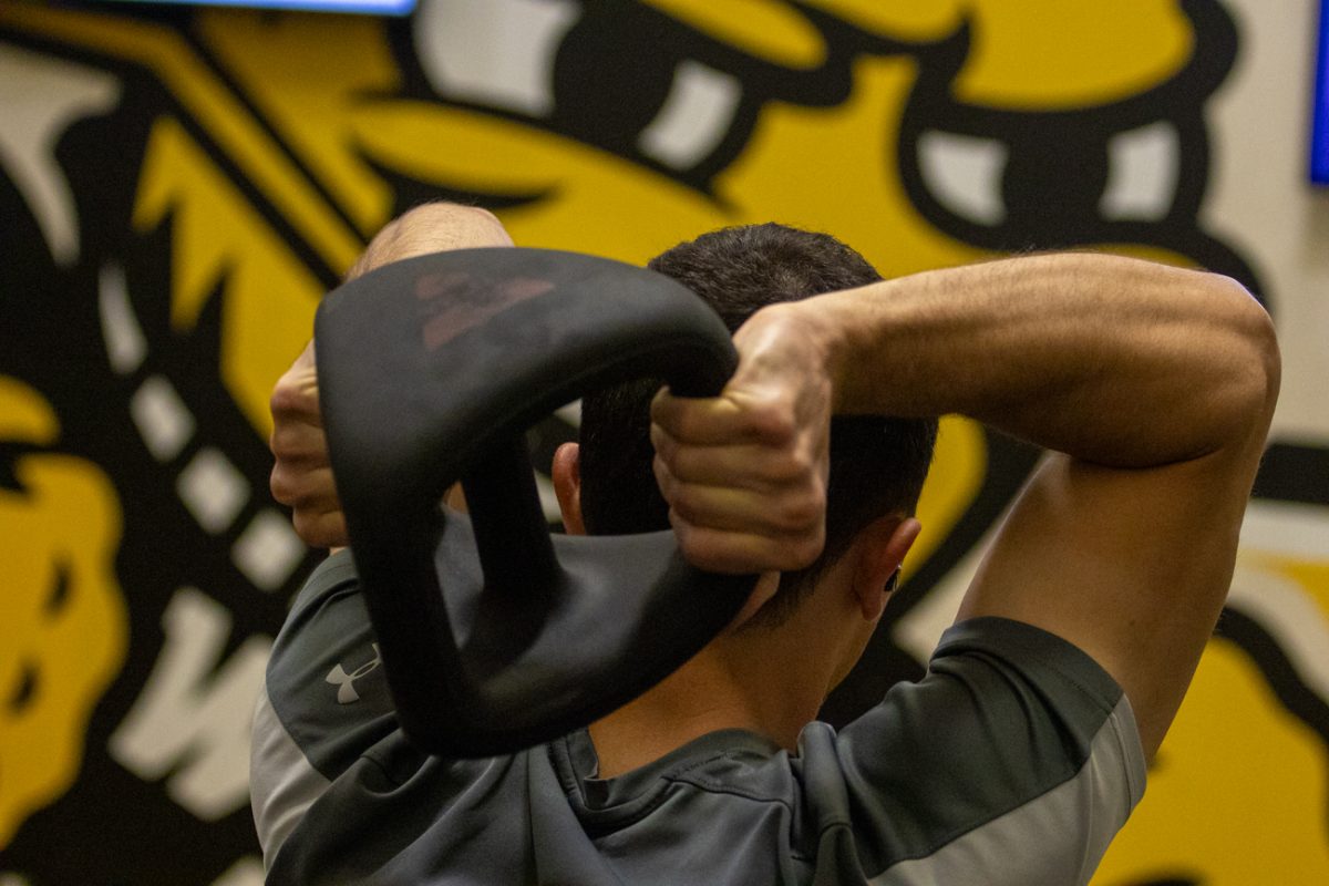Austin Raetzel puts a weight over his head for F45 workout routine. The Wichita State alum works at Deloitte.