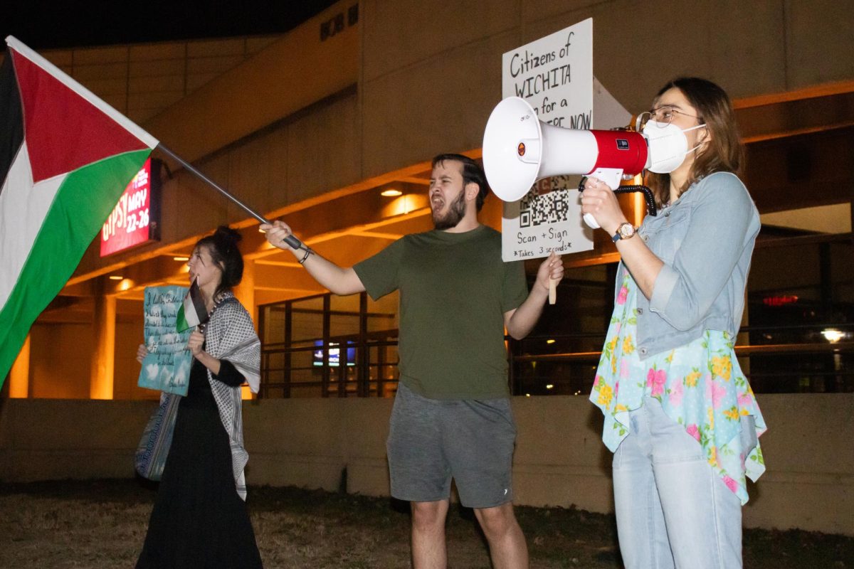 WSU students Kendah Ballout (right) and Sean Wentling (center) recite chants during the ceasefire protest at Century II Convention Center on Monday, Feb. 26. The group of Palestine supporters marched along Douglas Avenue and in front of Century II as guests filtered into the concert hall for Jordan Petersons We Who Wrestle with God event.