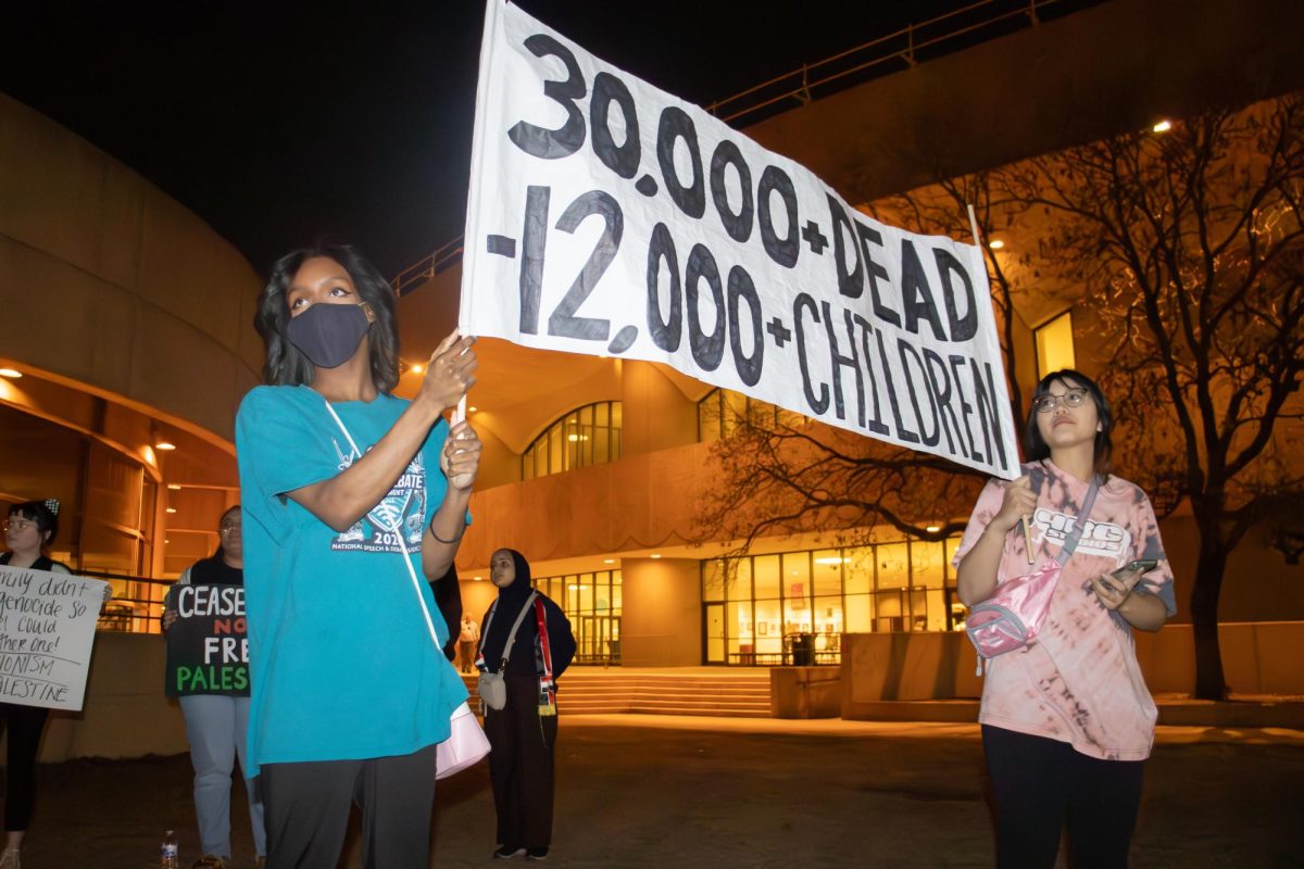 Protest attendees hold a banner with figures representing the number of murdered Palestinians. More than a dozen students and community members gathered outside of Century II on Monday evening to call for a ceasefire in the war between Israel and Palestinians.