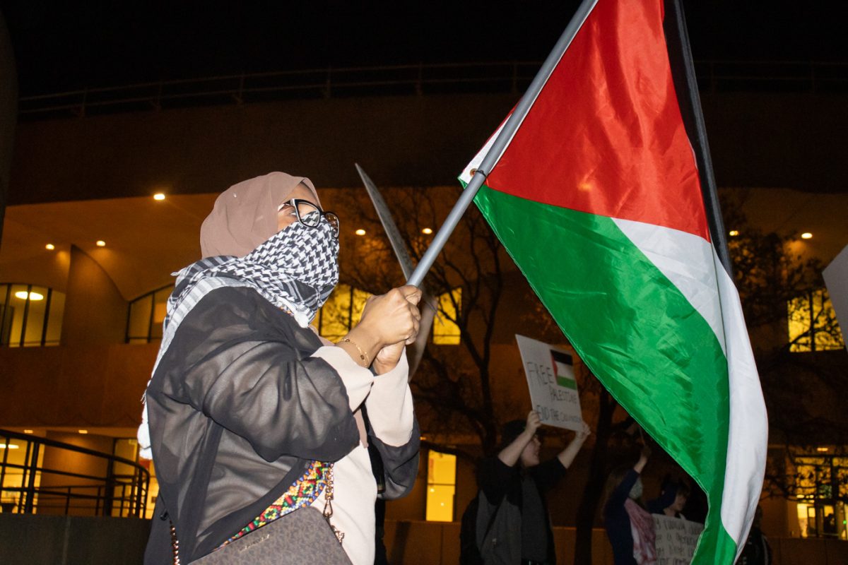 A Wichita community member waves a Palestinian flag during the protest at Century II on Monday, Feb. 25. Pro-Palestine supporters gathered outside of the convention center and along Douglas Avenue to voice their disdain toward Jordan Peterson and to demand a ceasefire in the Israel-Palestine war.