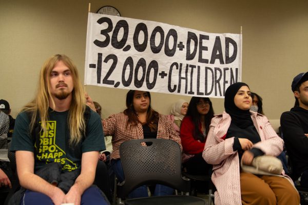 Olivia Ramos and another Wichita State student hold up a banner reflecting the number of Palestinian lives lost since the start of Israeli bombings in Gaza. Dozens of community members, students and WSU faculty and staff assembled at the Student Senate meeting on Wednesday night to call for a ceasefire in Gaza.
