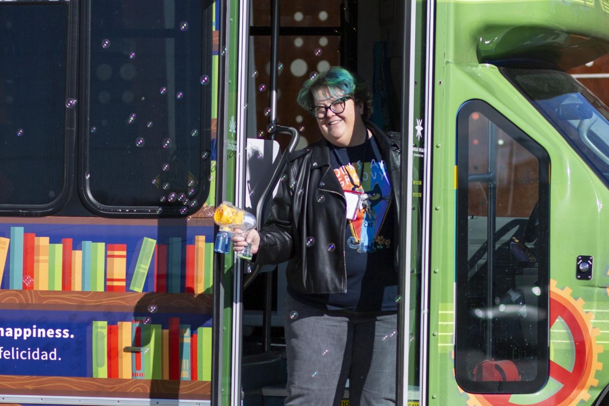 Racine Zackula, family literacy coordinator for the Wichita Public Library, poses with the Wichita Public Librarys Book Bus while creating bubbles with a handheld toy. If shes not on the road, Zackula spends much of her time planning where to take the Book Bus next.